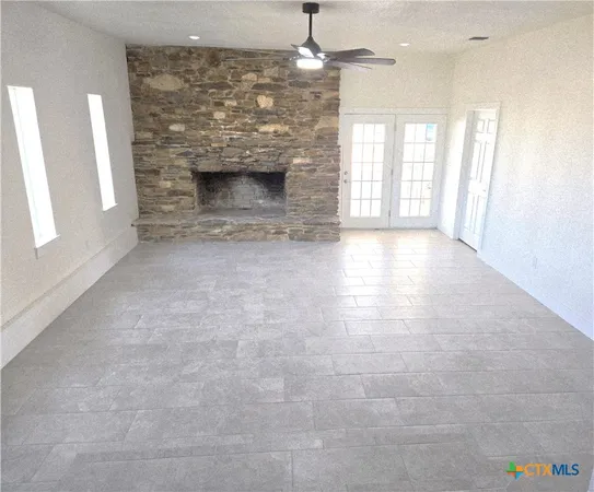 an empty room with windows and fan
