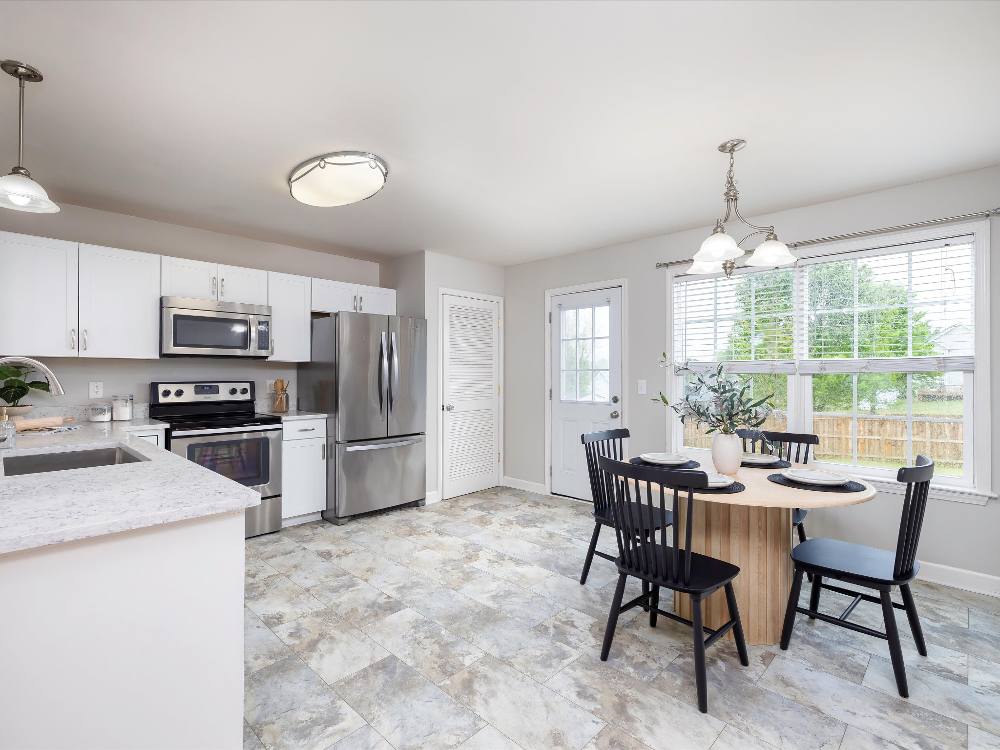 1007 Persimmon Drive Spring Hill, TN 37174 - Photo 14 of 44 a kitchen with stainless steel appliances a dining table chairs stove refrigerator and microwave