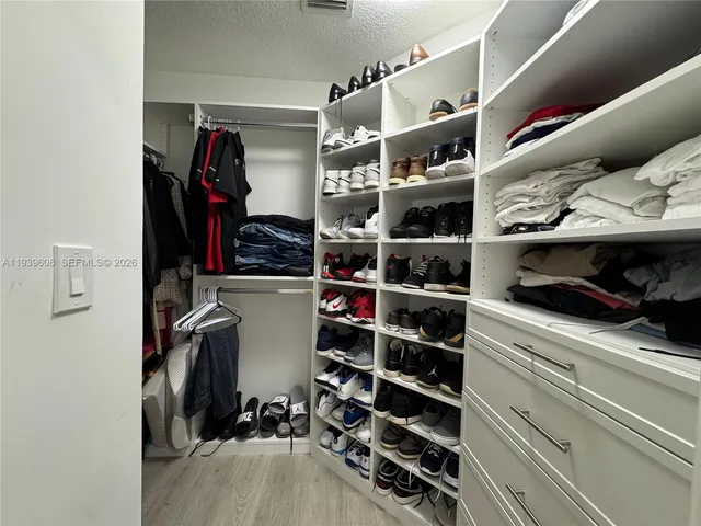 a view of walk in closet with clothes and shoes