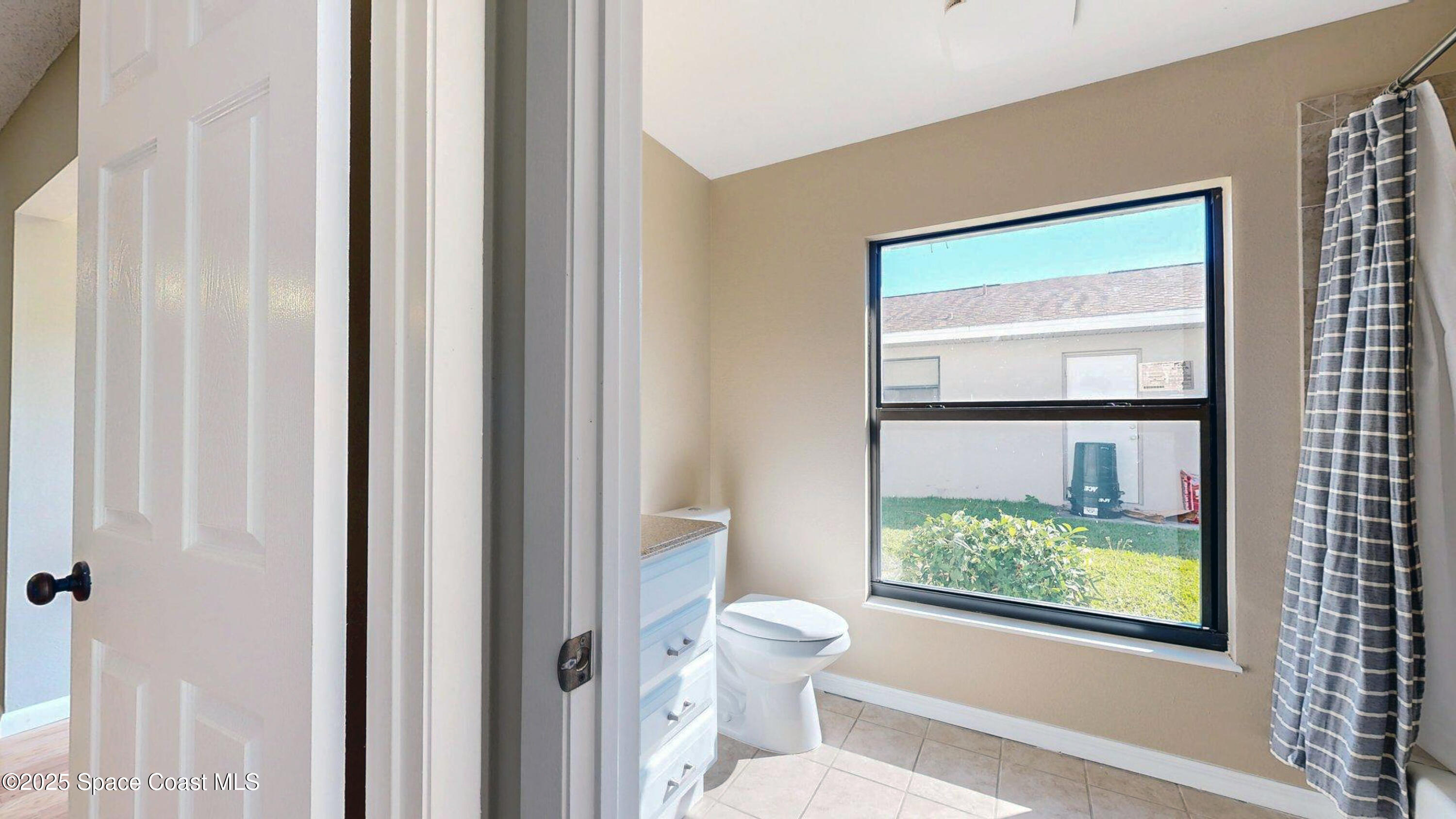 800 Inverness Avenue Melbourne, FL 32940 - Photo 14 of 22 a bathroom with a toilet sink and a large mirror next to a window