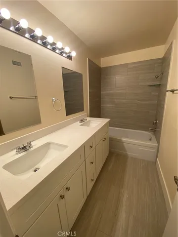 a bathroom with a double vanity sink a mirror and a bathtub