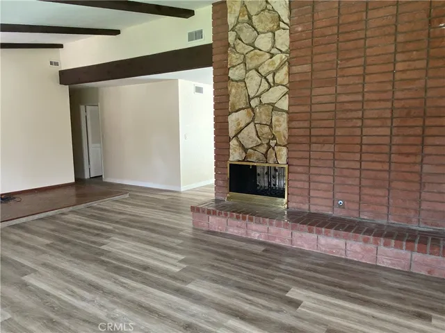 a view of an empty room with wooden floor and a fireplace