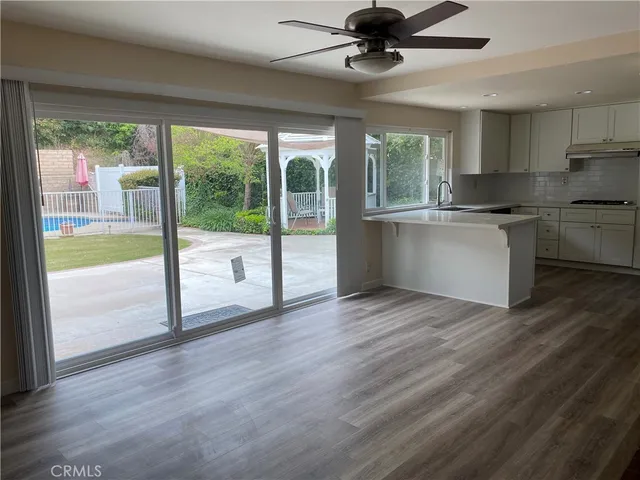 a kitchen with a large window a ceiling fan and wooden floor