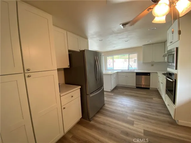 a kitchen with a refrigerator a stove top oven and wooden floor