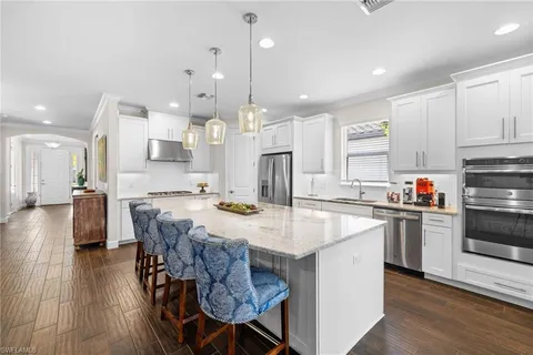 a large kitchen with kitchen island a stove a table a sink and a refrigerator