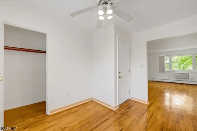 a view of empty room with wooden floor and fan