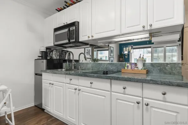 a kitchen with granite countertop white cabinets stainless steel appliances and a sink