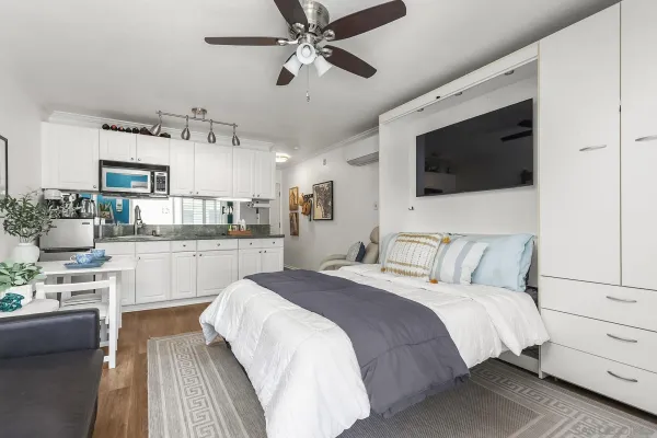 a bedroom with a large bed a flat screen tv and kitchen view