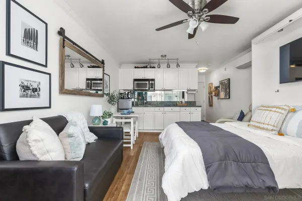 a living room with stainless steel appliances furniture and a kitchen