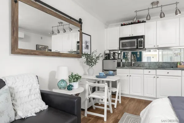 a kitchen with stainless steel appliances kitchen island granite countertop a refrigerator a stove a sink dishwasher and white cabinets with wooden floor
