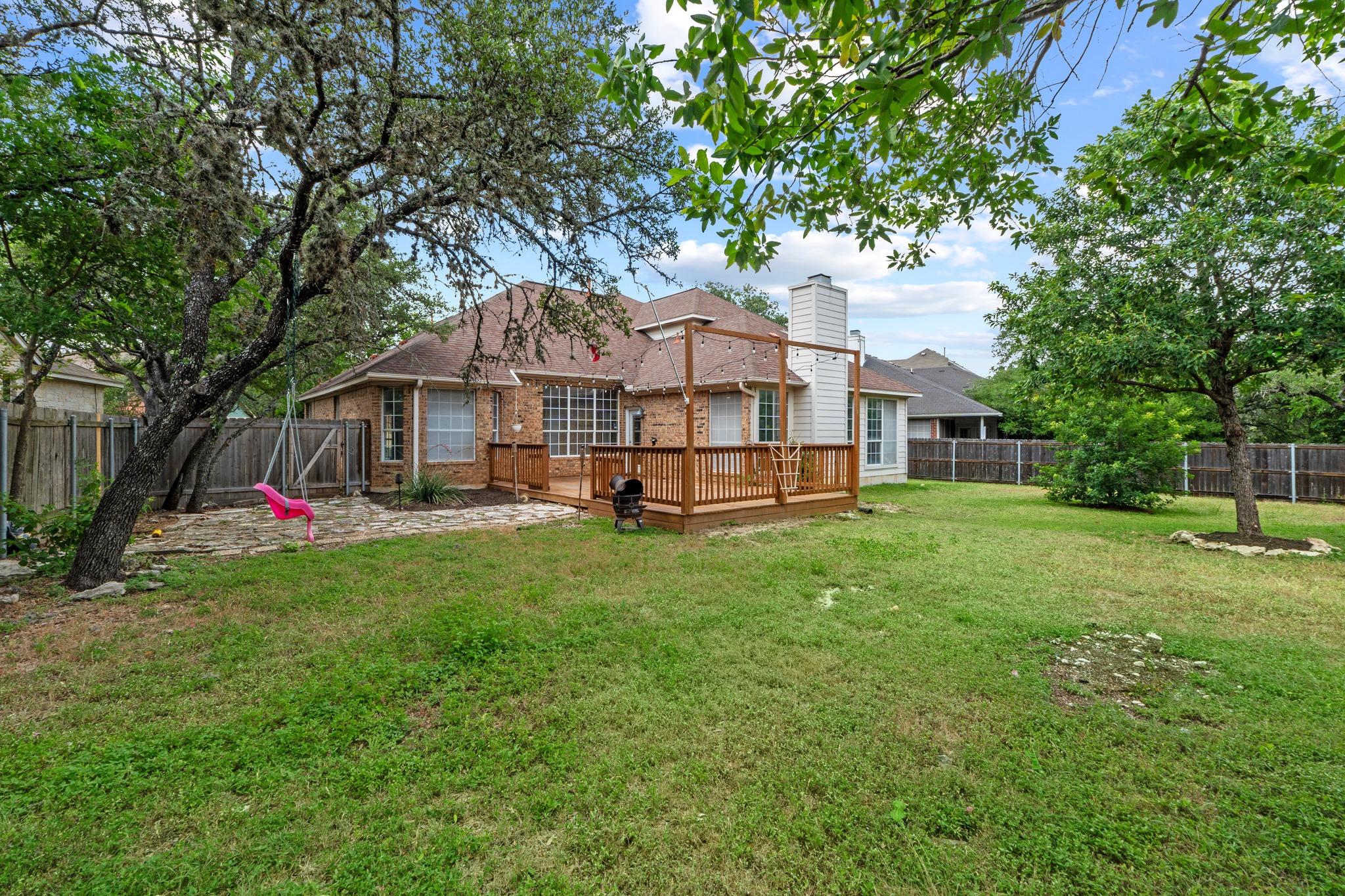 8605 Axis Drive Austin, TX 78749 - Photo 35 of 38 A spacious backyard features a wooden deck and ample green space for outdoor activities.
