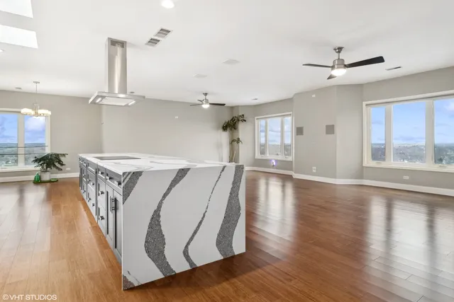 a view of a kitchen with kitchen island a refrigerator wooden floor and a large window