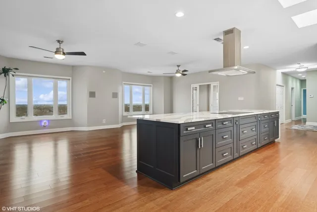 a large kitchen with stainless steel appliances a large counter top a sink a chimney and a large window