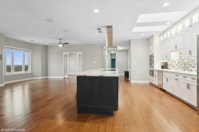 a large kitchen with a center island wooden floor stainless steel appliances and cabinets