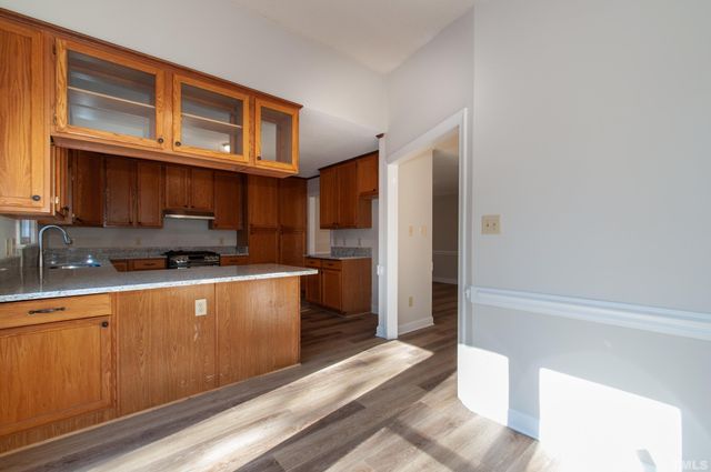 a kitchen with stainless steel appliances granite countertop a refrigerator a stove and a sink with wooden cabinets