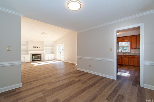 a view of a kitchen and an empty room with a window
