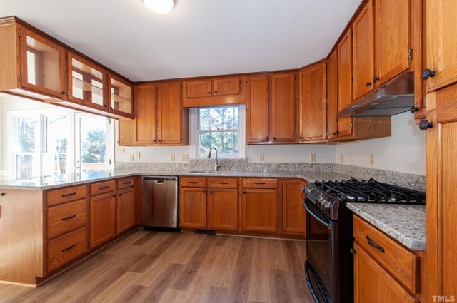 a kitchen with granite countertop wooden cabinets a stove a sink and a window