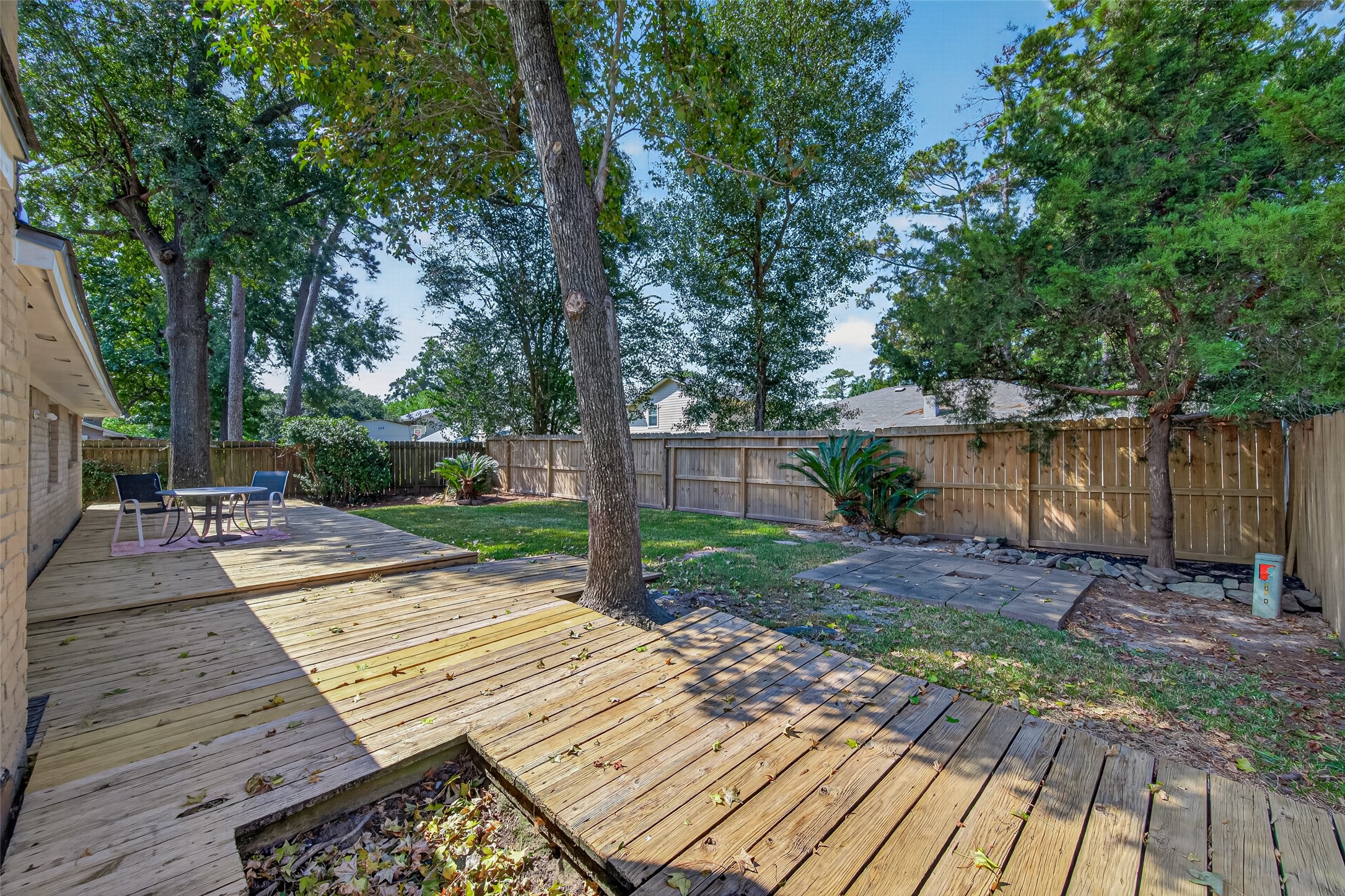 23219 Calico Corners Lane Spring, TX 77373 - Photo 21 of 24 Spacious backyard featuring a large wooden deck, perfect for outdoor entertaining, surrounded by mature trees and a privacy fence.