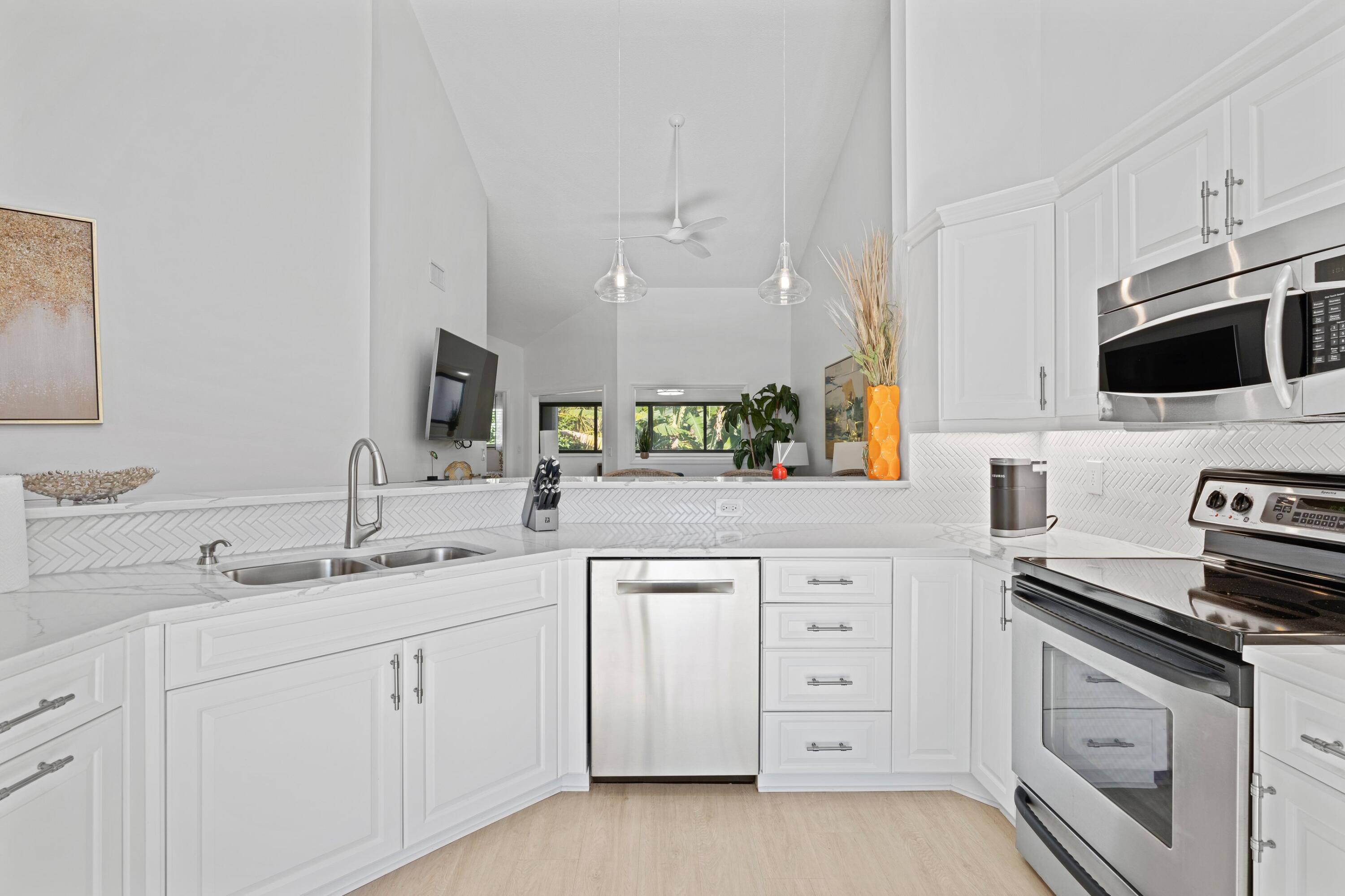 202 Sea Oats Drive Juno Beach, FL 33408 - Photo 5 of 17 a kitchen with white cabinets and appliances