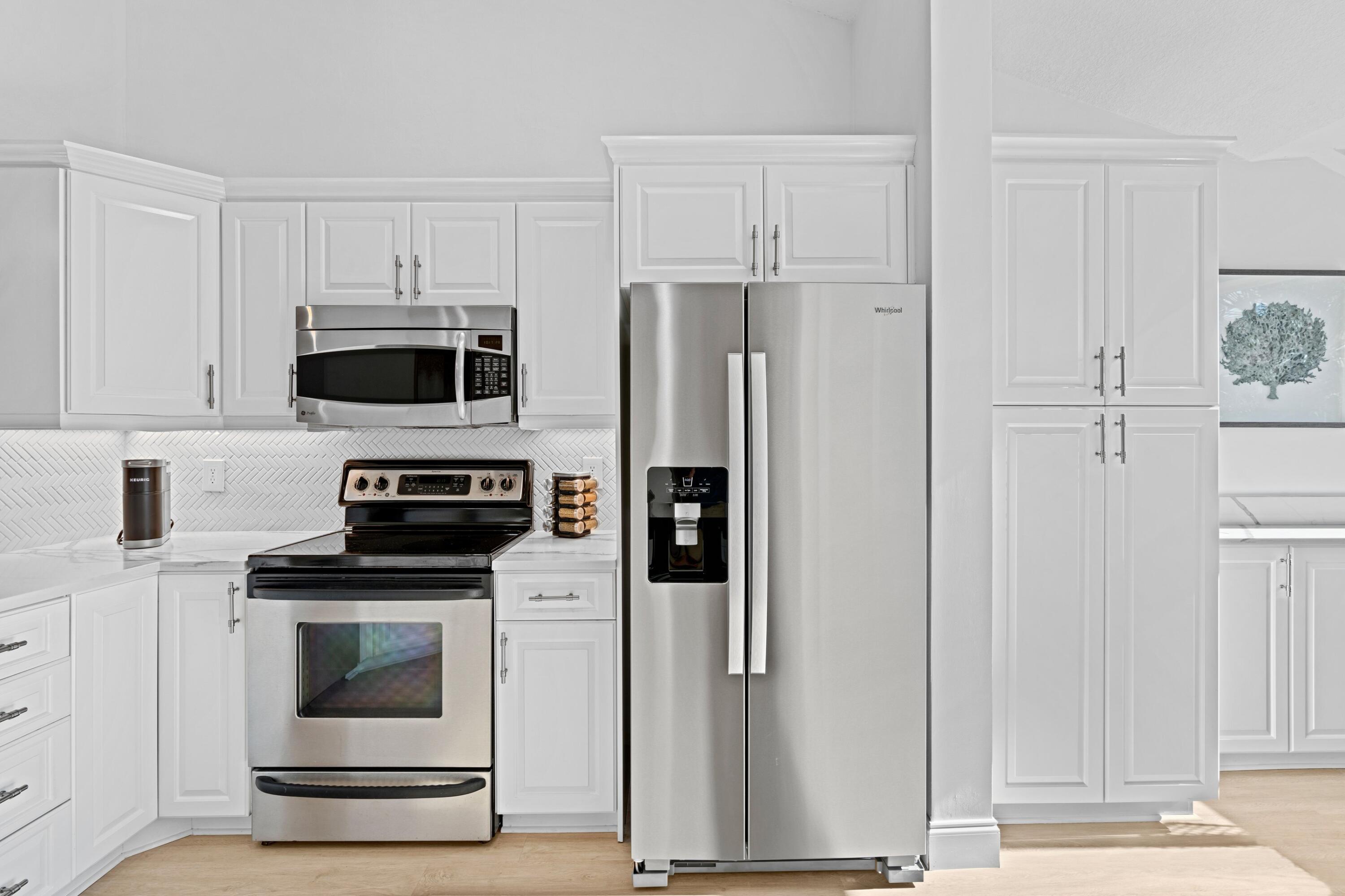 202 Sea Oats Drive Juno Beach, FL 33408 - Photo 7 of 17 a kitchen with white cabinets and stainless steel appliances