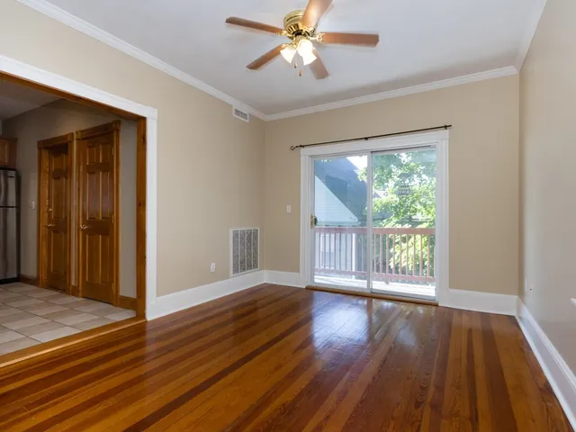 a view of an empty room with wooden floor and a window