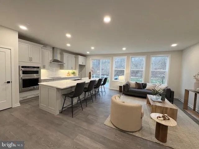a living room with couches and kitchen view with wooden floor