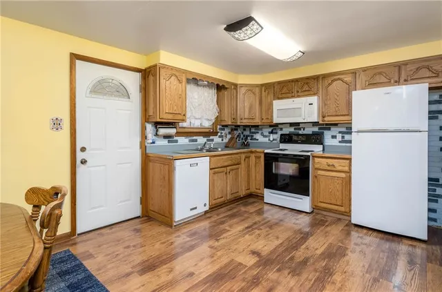 a kitchen with stainless steel appliances granite countertop a stove top oven a refrigerator a sink and dishwasher with white cabinets