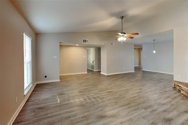 a view of a room with a ceiling fan window and wooden floor