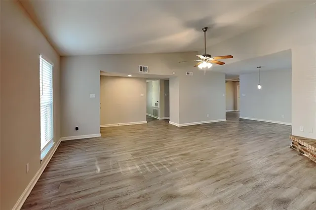a view of a room with a ceiling fan window and wooden floor