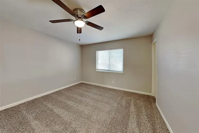 an empty room with a window and a ceiling fan