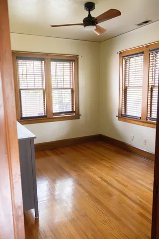 an empty room with wooden floor chandelier and windows