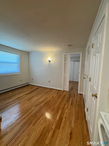 a view of empty room with wooden floor and fan