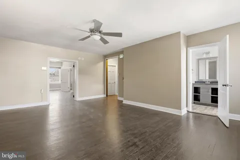 a view of a big room with wooden floor a ceiling fan and windows