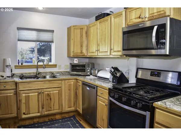 a kitchen with stainless steel appliances granite countertop a stove a sink and a microwave