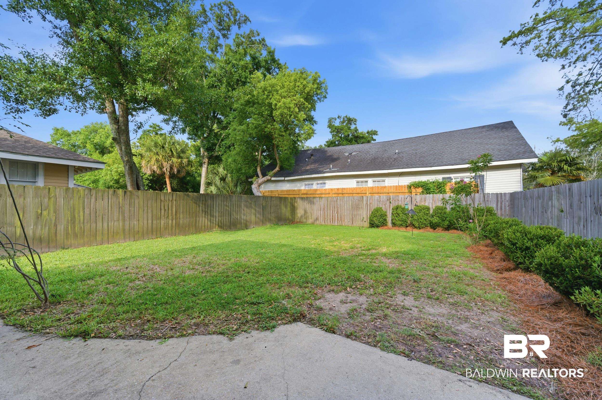 350 Charles Street Mobile, AL 36604 - Photo 52 of 52 Expansive backyard featuring a lush lawn, mature trees, wood privacy fencing, and concrete patio space