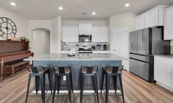 a kitchen with stainless steel appliances granite countertop a dining table chairs refrigerator microwave and cabinets