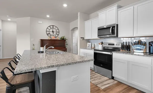 a kitchen with stainless steel appliances granite countertop a sink dishwasher stove and microwave with wooden floor