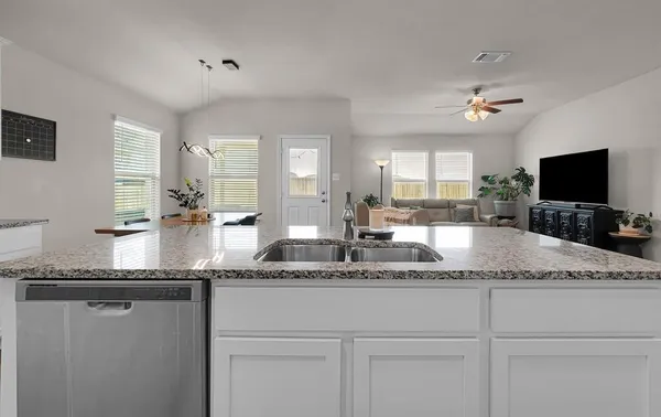 a kitchen with granite countertop a sink a counter top space and cabinets