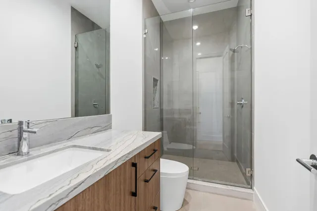 a bathroom with a granite countertop sink a toilet and shower