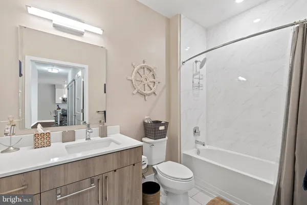 a bathroom with a bathtub shower sink vanity mirror and toilet