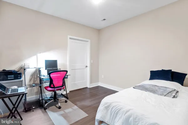 a bedroom with a bed a chair and a bookshelf with wooden floor