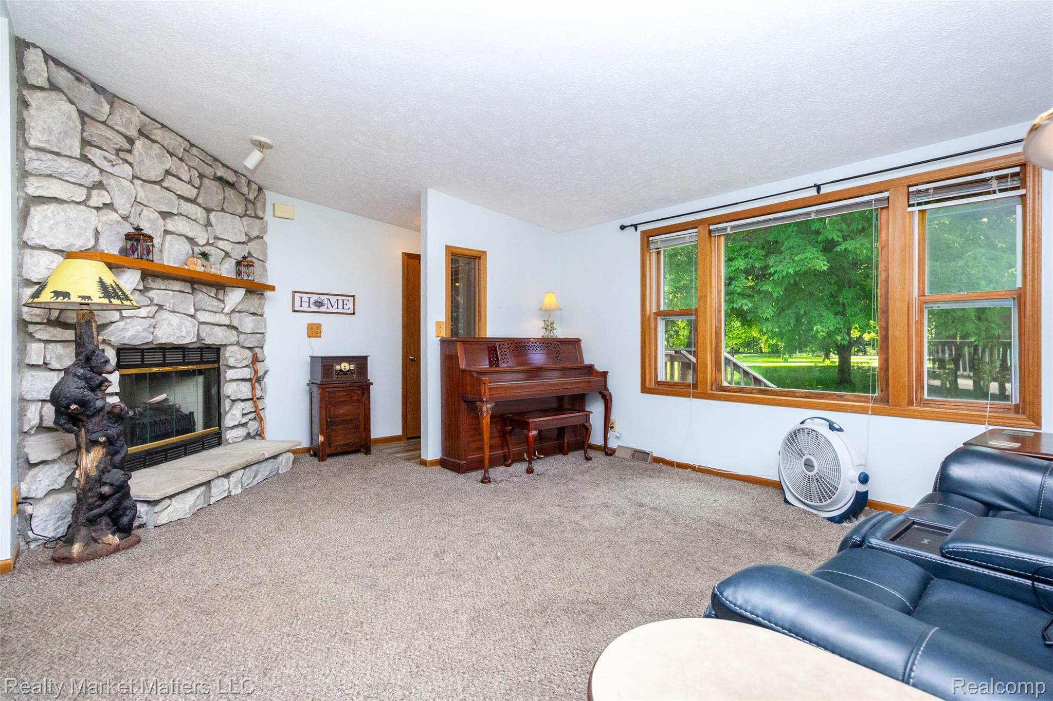 4951 Laur Road North Branch, MI 48461 - Photo 3 of 34 Living area featuring a stone-clad fireplace with a wood mantel, a hearth, and large picture windows with wood trim