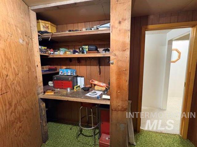 3197 Neeley Road American Falls, ID 83211 - Photo 35 of 45 Utility space featuring built-in shelving, a built-in workbench, wood paneling, and green carpeting