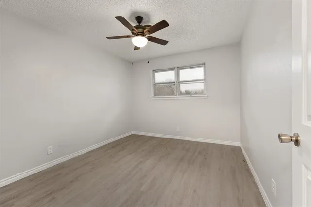 an empty room with a window and ceiling fan