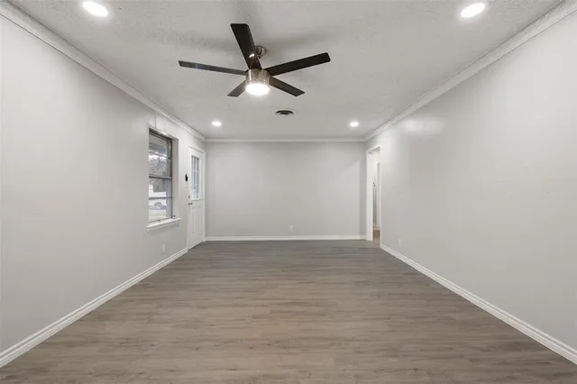 an empty room with wooden floor ceiling fan and windows