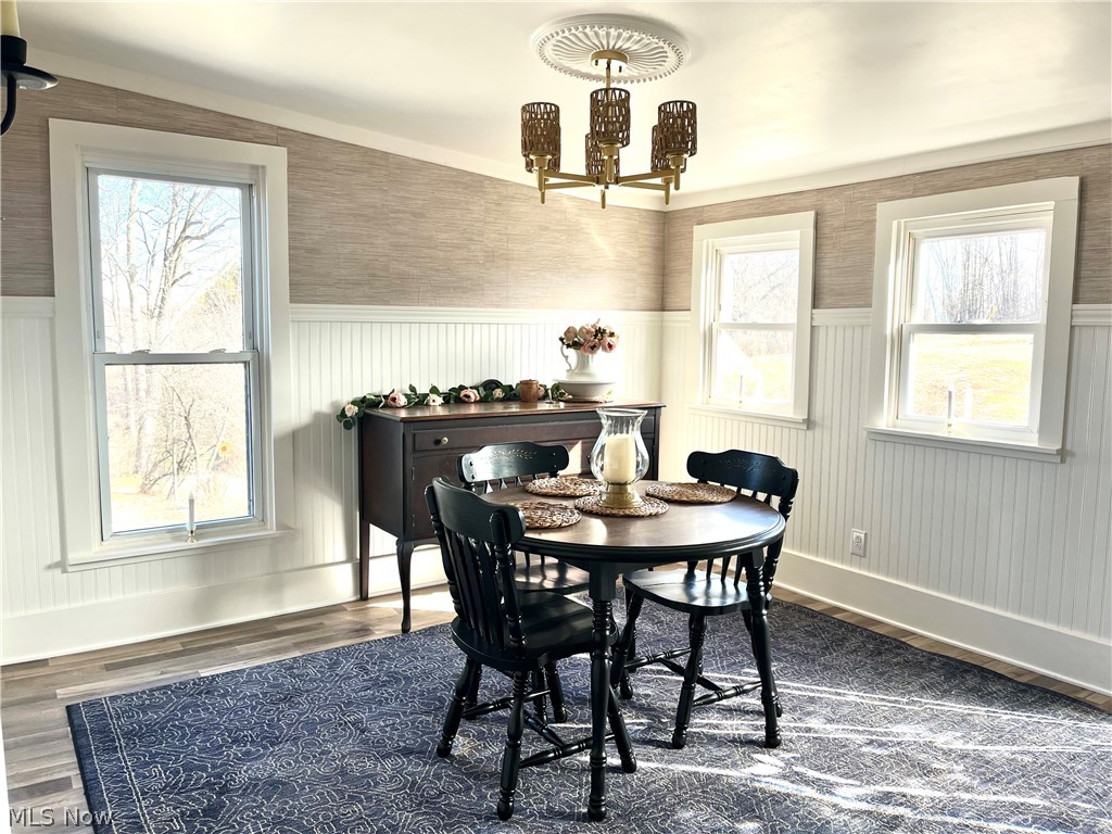 12972 Gilmore Road Southeast Port Washington, OH 43837 - Photo 6 of 50 Dining space featuring wainscoting, healthy amount of natural light, hanging lights, dark wood finished floors, and wallpapered walls
