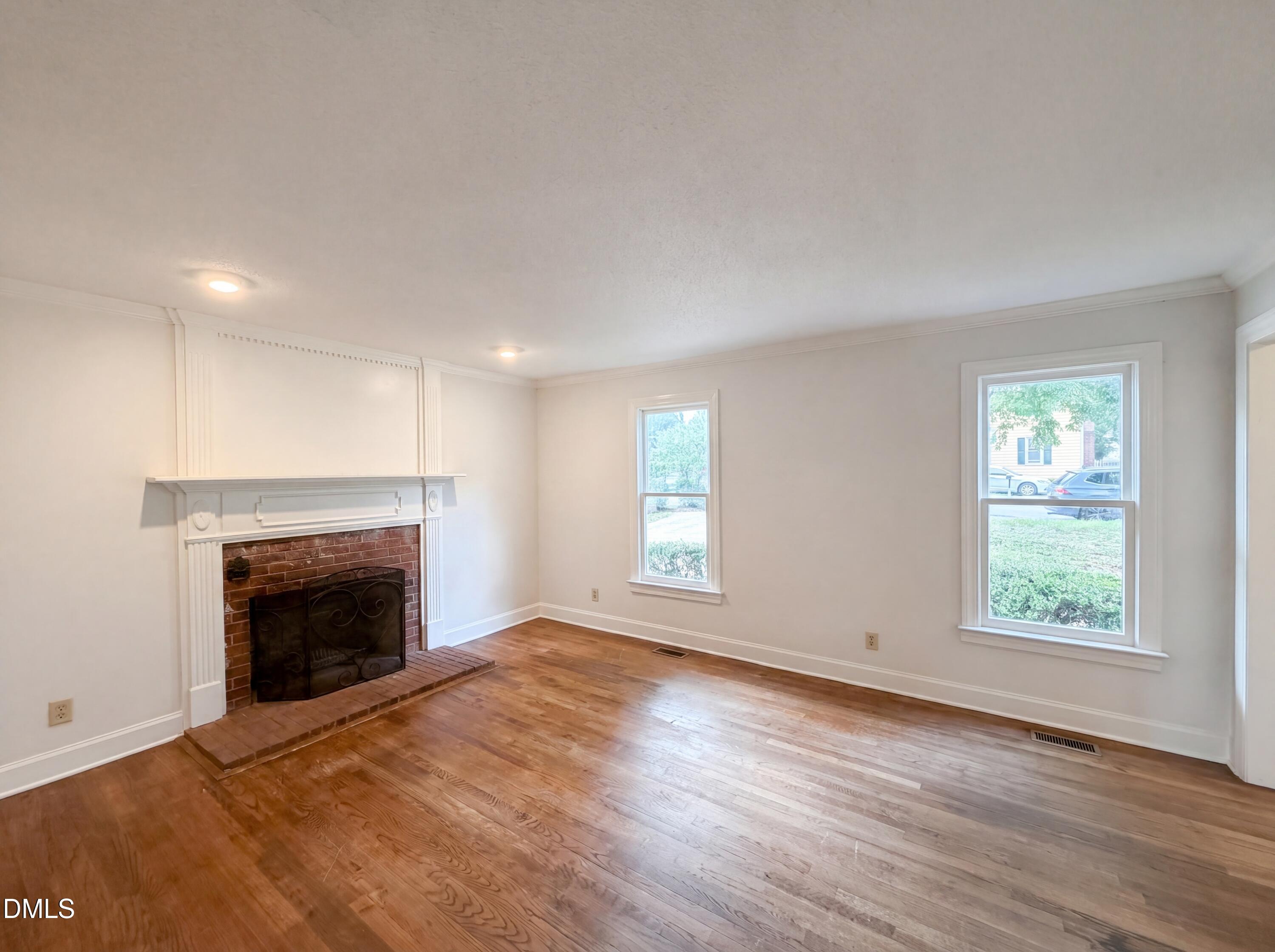 3921 Iron Horse Road Raleigh, NC 27616 - Photo 3 of 20 an empty room with wooden floor fireplace and windows