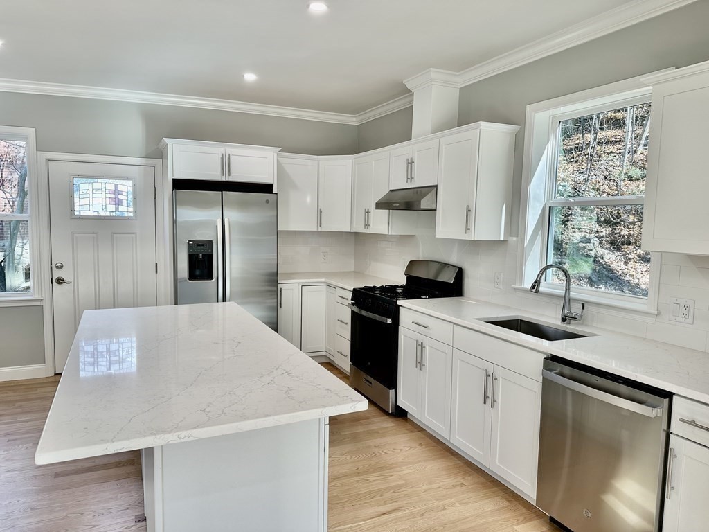 a kitchen with granite countertop a sink stainless steel appliances and white cabinets