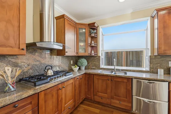 a kitchen with granite countertop a sink a stove and cabinets