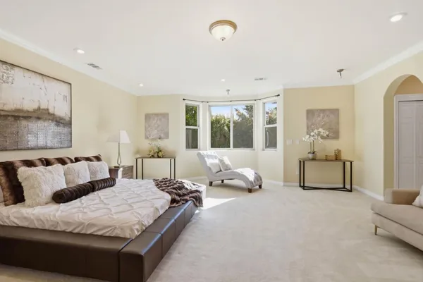 a spacious bedroom with a bed and glass walk in closet